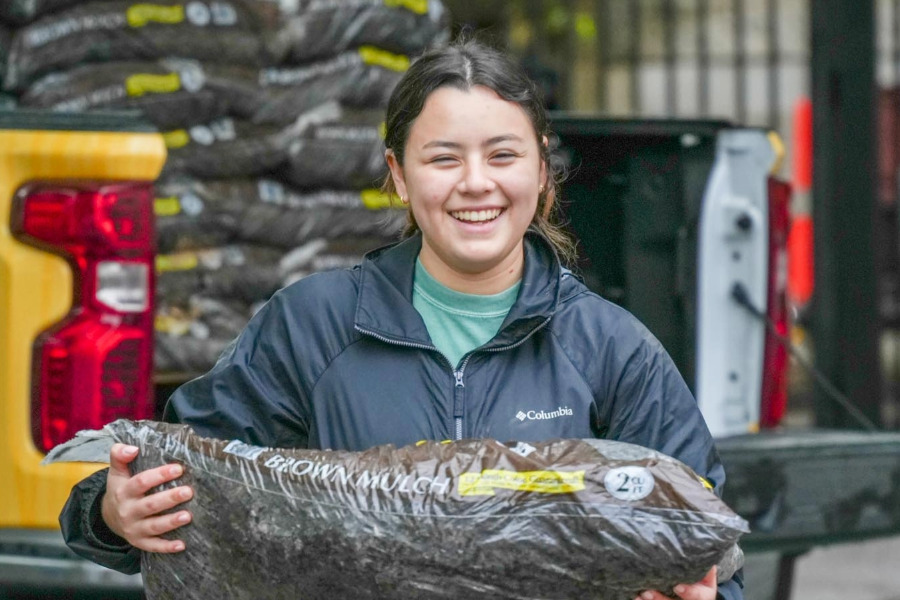 A student carrying a bag of mulch