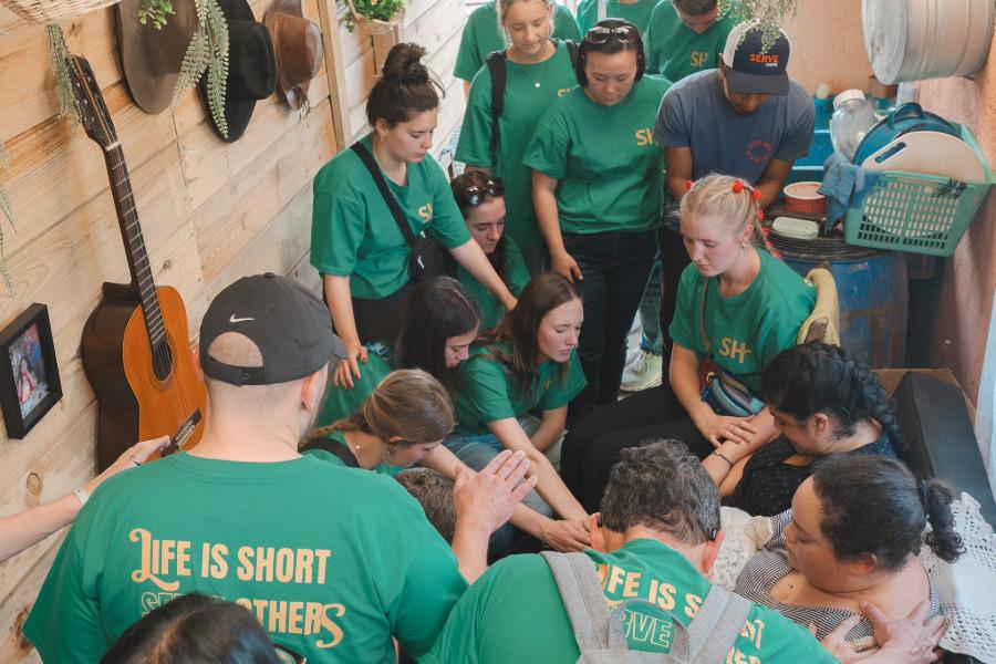 Students praying over a family on a Baylor mission trip